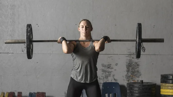 Entrenamiento femenino fuerte joven del levantador de pesas en el gimnasio, tiro del primer plano Fotos de stock