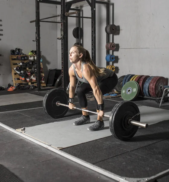 Strong female weight lifter preparing to lift barbell. Stock Picture