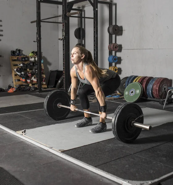 Sterke vrouwelijke gewicht lifter voorbereiden op tillen barbell. Stockfoto