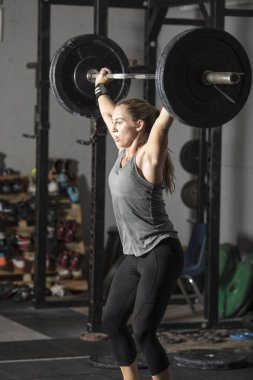 Spor salonunda ağır ağırlıkile güçlü genç kadın powerlifting