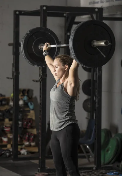 Strong young woman lifting heavy weights over her head Royalty Free Stock Images