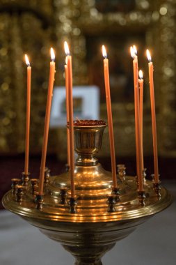 turuncu mumlar demir bir mum çubuğunda duruyor ve ateş yanıyor