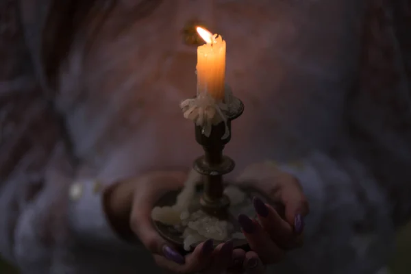 Orange candle in a candlestick and hold her hands — Stock Photo, Image