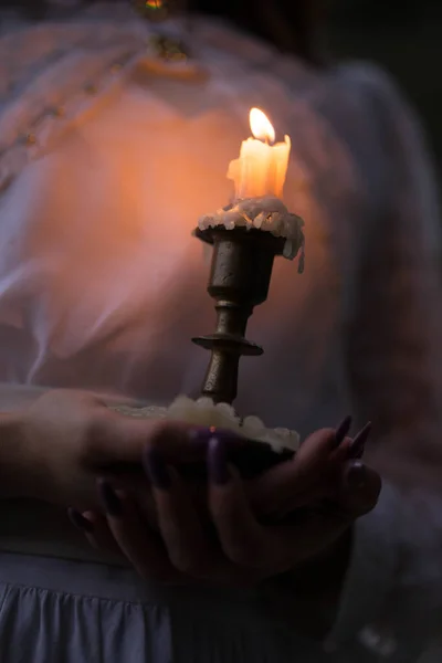 Orange candle in a candlestick and hold her hands — Stock Photo, Image