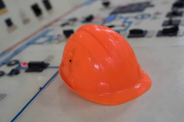 Um capacete laranja está no painel de trabalho — Fotografia de Stock