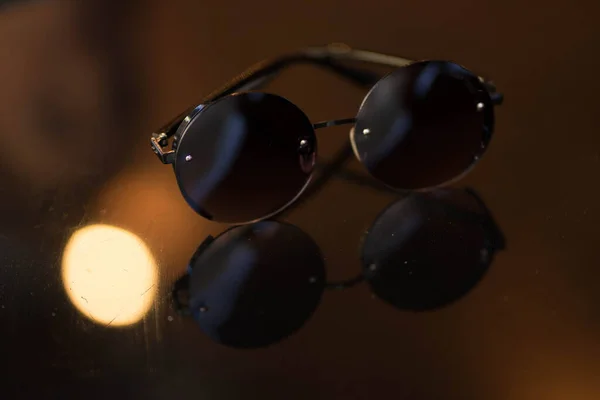 Sluneční brýle s kulatými brýlemi leží na stole — Stock fotografie