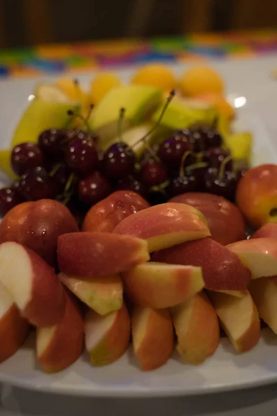 Frutas yacen en un plato blanco sobre la mesa — Foto de Stock