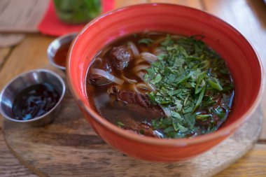 Etli çorba ve soslu kil tabakta erişte.