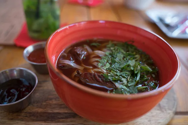 Suppe mit Fleisch und Nudeln in einem Tonteller mit Soßen — Stockfoto