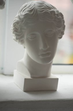 Beyaz alçı heykeller pencere eşiğinde duruyor.