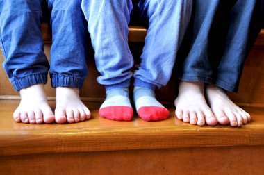 üç küçük çocuğun bacakları ahşap bir merdiven üzerinde duruyor