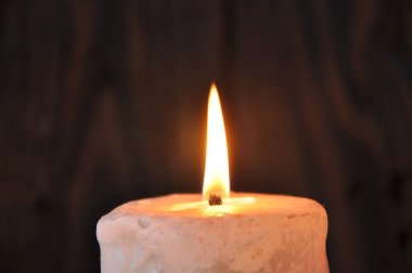 büyük bir mum ahşap bir doku arka plan üzerinde karanlıkta yanar