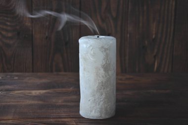 karanlıkta söndürüldü büyük mum. Ahşap bir arka plan üzerinde. Mum dumanı