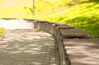 parkta bir taş yükseklik üzerinde eski ahşap banklar