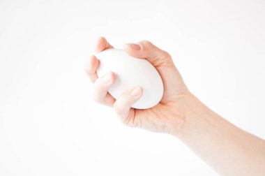 elinde beyaz bir arka plan üzerinde büyük bir beyaz yumurta tutar