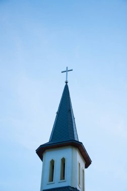 Katolik kilise binasında haçla kule. Gökyüzüne karşı
