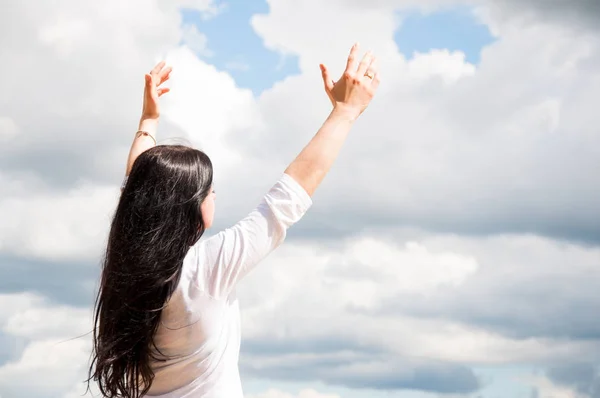 一个女人站起身来 举起双臂 向上帝祈祷 夏天在绿茵场上 蓝天白云 — 图库照片