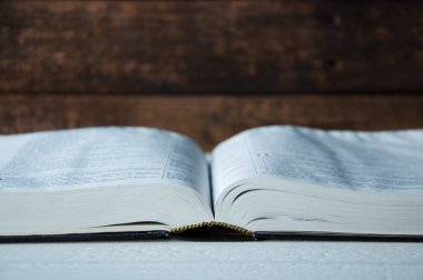Büyük bir kitap ahşap bir masa üzerinde açık yatıyor.