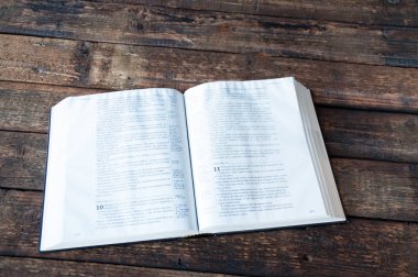 Büyük bir kitap ahşap bir masa üzerinde açık yatıyor.