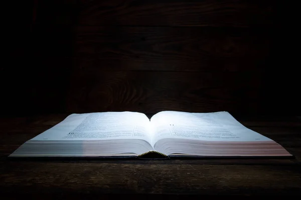 聖書の大きな本は木製のテーブルの上にあります 分からない 上から本に光が輝く — ストック写真