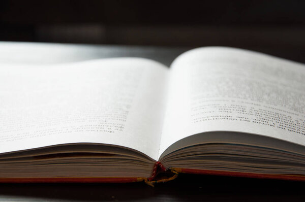 Открытая книга на столе. На тёмном фоне. Крупный план
