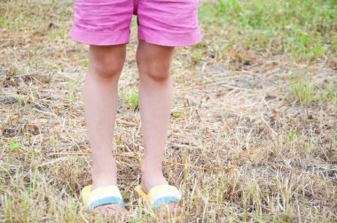 şort ve flip-flop biçilmiş çim üzerinde duran küçük kız