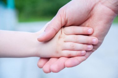 anne küçük bir çocuğun elini tutar. El ele.