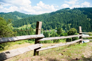 Dağlarda eski ahşap çit. Orman ve uzun ağaçlar. Dağlar ve tepeler. Yaz