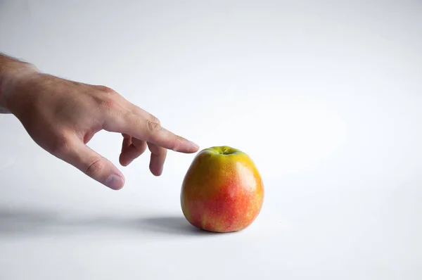 Una Mela Poggia Tavolo Bianco Uno Sfondo Bianco Mano Prende — Foto Stock