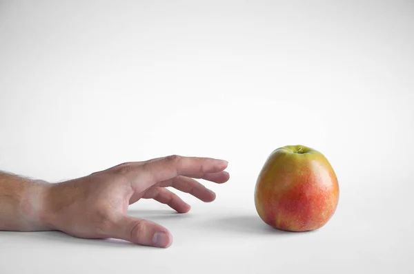 Una Mela Poggia Tavolo Bianco Uno Sfondo Bianco Mano Prende — Foto Stock