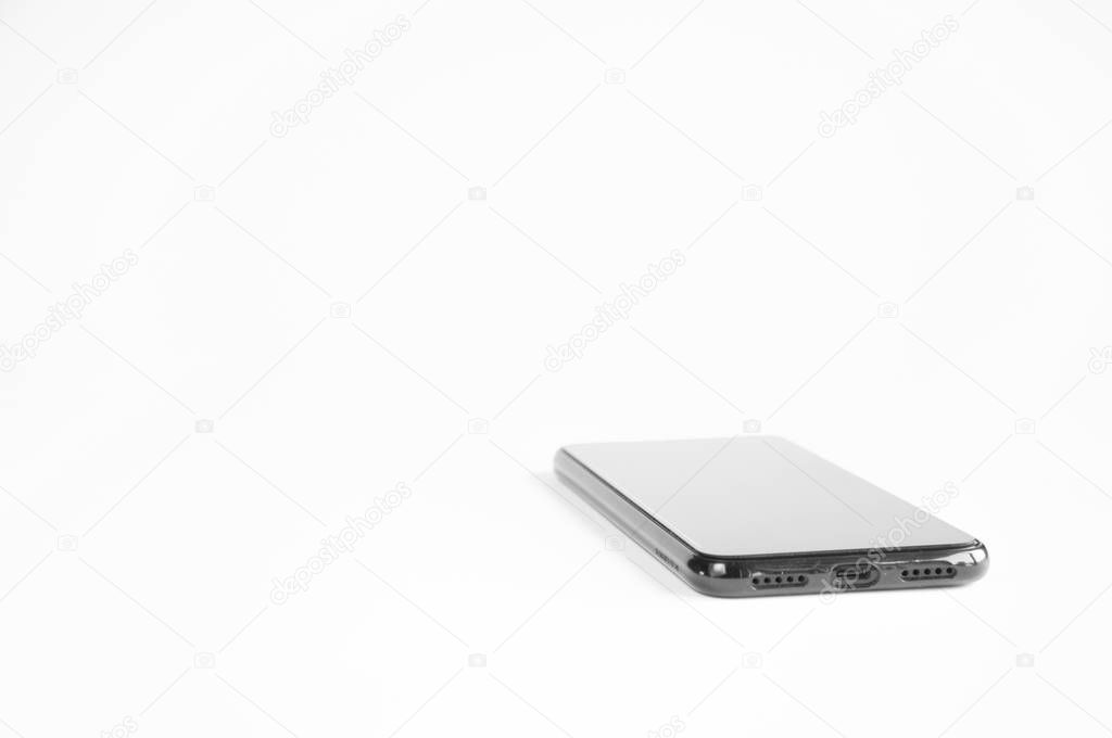 Black smartphone lies on a table on a white background.