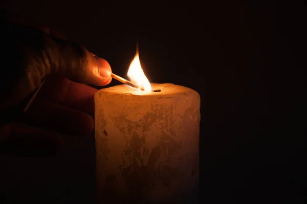 燃烧的火柴在手 点燃一支蜡烛 在黑暗中 在黑色背景上 — 图库照片
