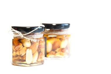 Masada bal ve fındık dolu cam kavanozlar. Beyaz arkaplanda.