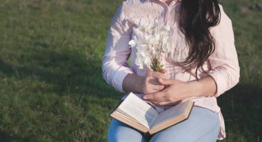Çiçekler ve genç bir kızın elinde bir kitap. Bahar ve yaz