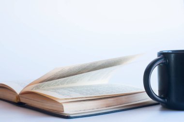 Açık bir kitap ve bir fincan. Arka planda. İncil