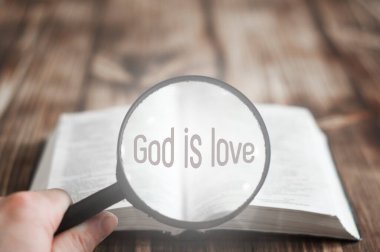 Tahta bir masada İncil 'i aç. Büyüteç. Tanrı sevgidir.