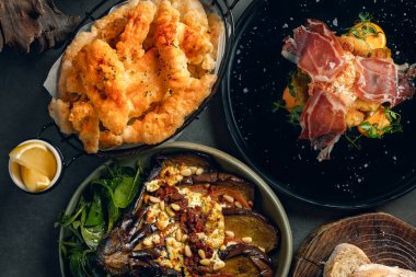 Kızarmış kalamar, ızgara patlıcan ve yumurtalı jambon karışımından oluşan lezzetli tapas seçimi.