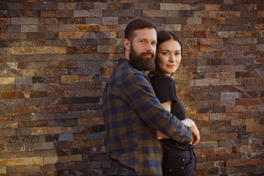 Şık genç çift zaman açık havada birlikte geçiriyor. Çekici kadın ve yakışıklı sakallı adam tuğla zemin üzerine poz.