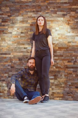 Çekici bir kaç yere güneşli bir günde şehirde oturuyor. Şık kadın ve yakışıklı sakallı adam tuğla zemin üzerine poz.