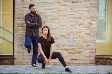 Çekici bir kaç yere güneşli bir günde şehirde oturuyor. Şık kadın ve yakışıklı sakallı adam tuğla zemin üzerine poz.