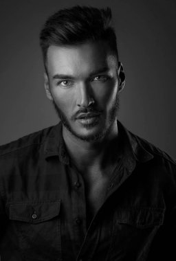 Siyah arka planda cesur erkeksi yüzü olan yakışıklı bir gencin yakın portresi. Beyaz adam ciddi bakıyor, erkek güzellik, kozmetik..