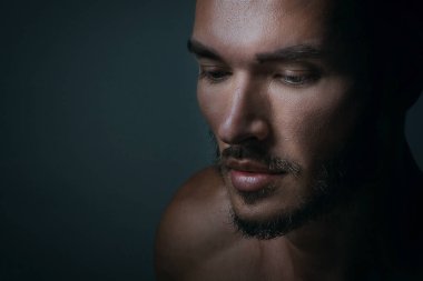 Siyah arka planda cesur erkeksi yüzü olan yakışıklı bir gencin yakın portresi. Beyaz adam ciddi bakıyor, erkek güzellik, kozmetik..