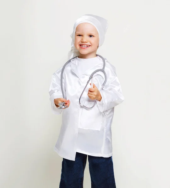 可爱的微笑小女孩与听诊器和温度计在医生服装 滑稽的2 岁女孩宽微笑显示牙齿 复制空间 灰色背景 — 图库照片