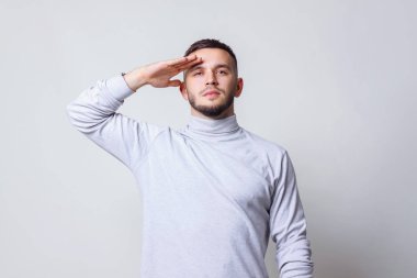 Selam kavramı. Casual Beyaz yaka gömlek gri arka plan kopya alanı alnına el ile selamlayan içinde genç adam