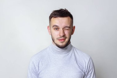 Yakışıklı adam kameraya bakarak ve göz kırpıyor. gri, kopya alanı izole