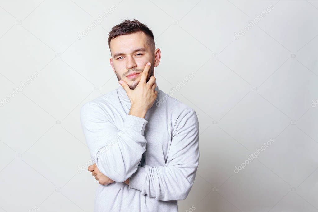 Portrait of a handsome young man thinking on something, isolated on gray background