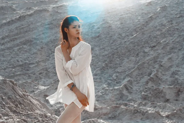 Woman with white dress walking in the desert sand dunes with footsteps in the desert sand, young woman walking sand on a bright summer day