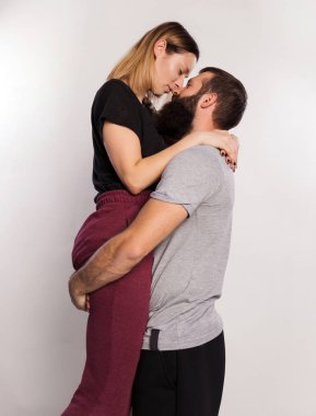 Romantik öpücükler. Mutlu genç adam taşıyan, sarılma ve güzel kızını öp. Güzel çift çekici kadın ve yakışıklı sakallı adam gri izole