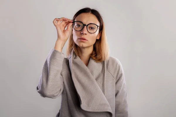 Studio Portret Kobiety Duże Okulary Stojąc Szary Płaszcz Prostuje Okulary — Zdjęcie stockowe