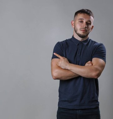 Göğsünü gri arka plan kopya alanı üzerinde dururken yanına parmak işaret casual adam kollarını ile bir gömlek giymiş portresi geçti